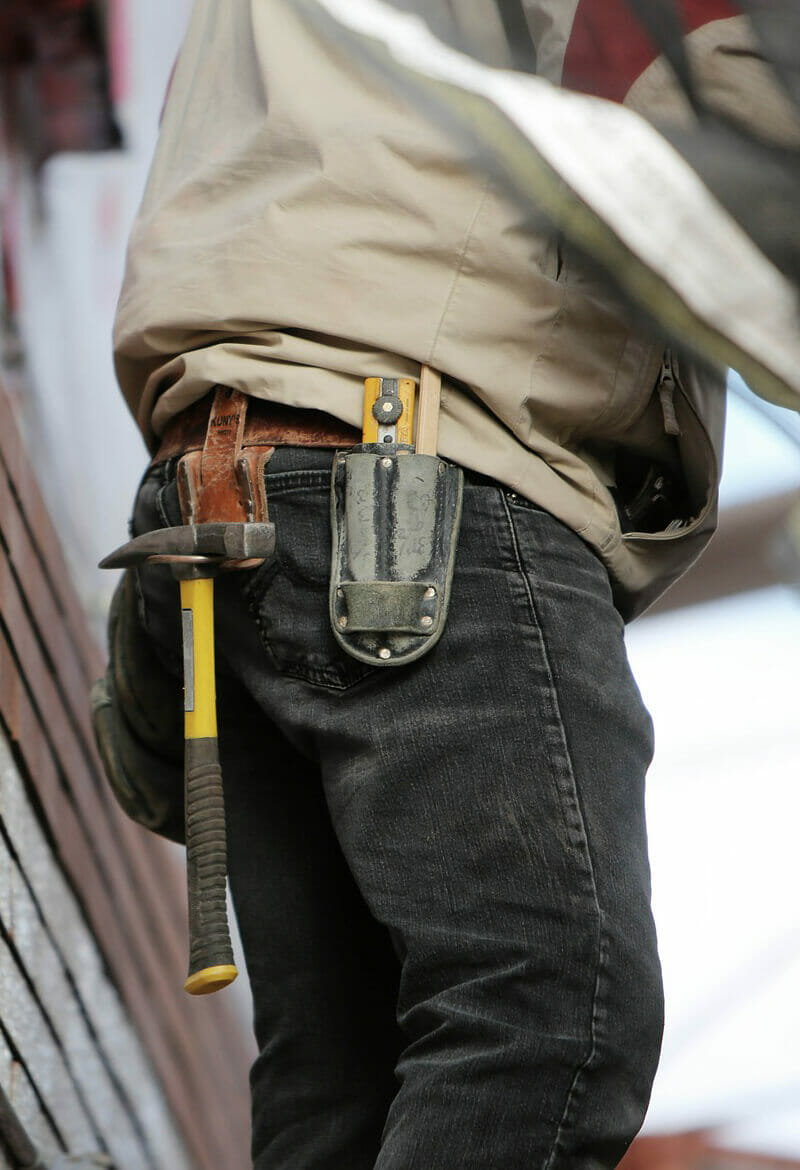 Construction worker with multiple tools tucked into his pants