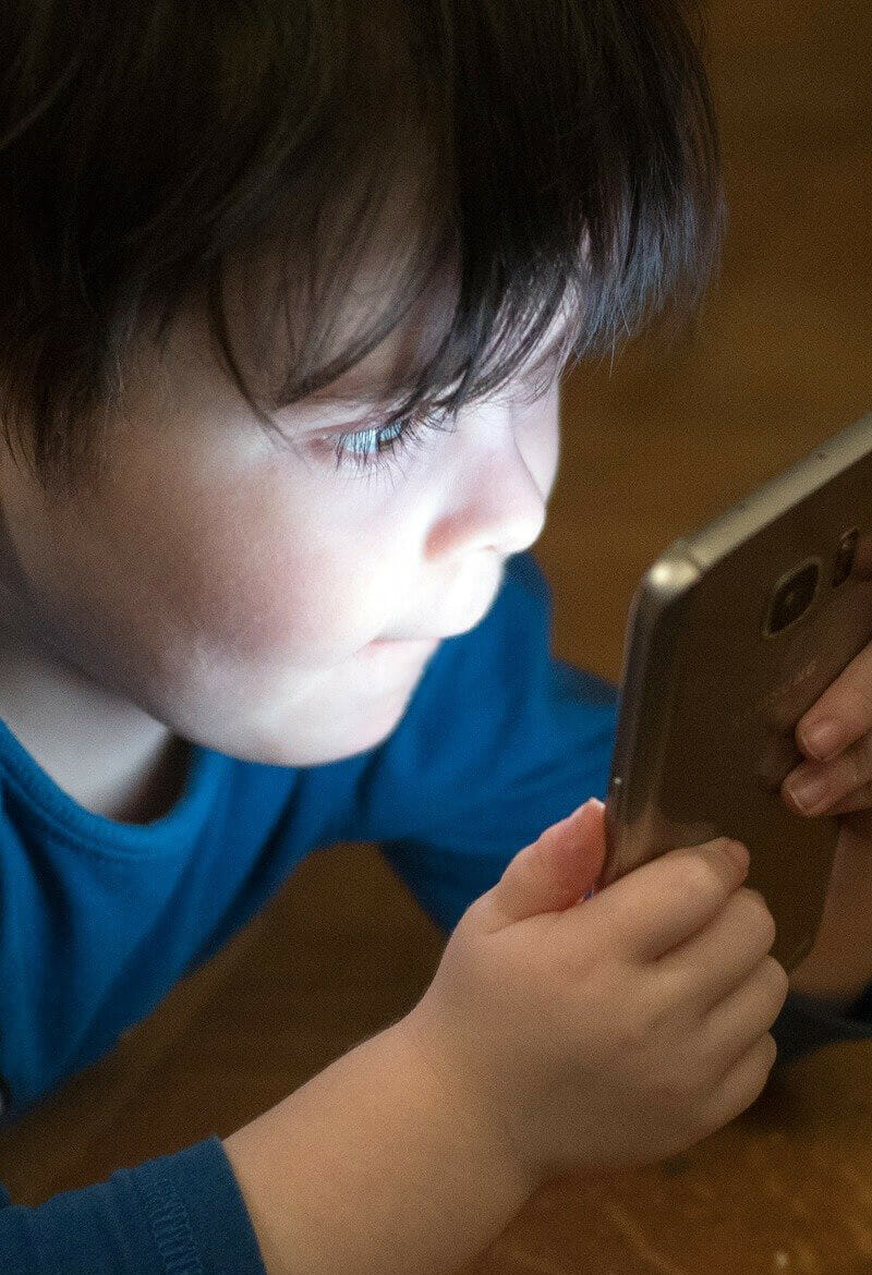 Small boy looks at the screen of a cell phone