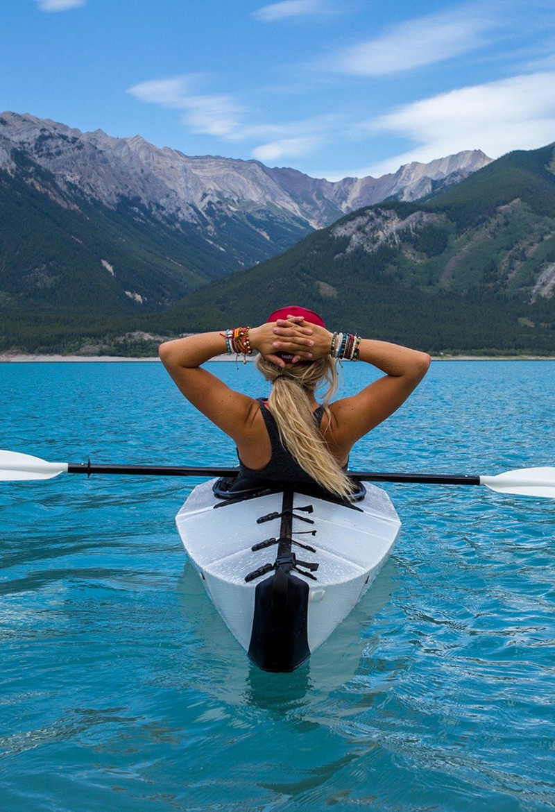 Women on the lake with hands behind her head relaxing.