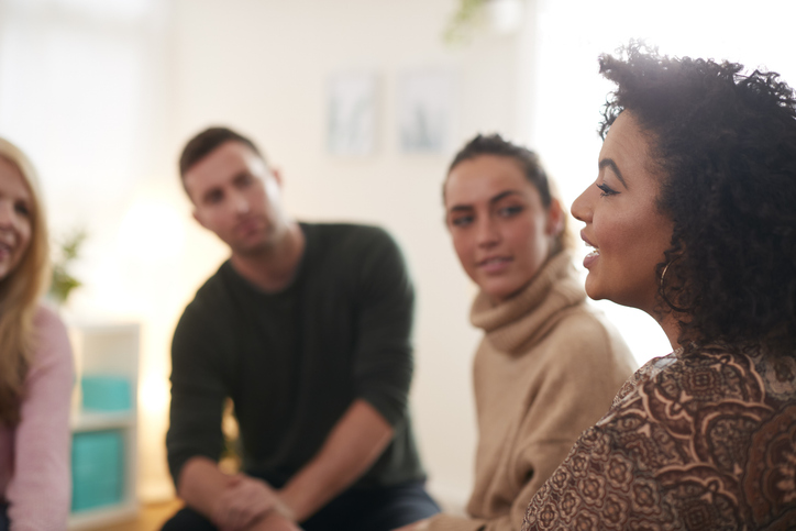 Woman speaking at a support group meeting in an outpatient addiction treatment and recovery care facility