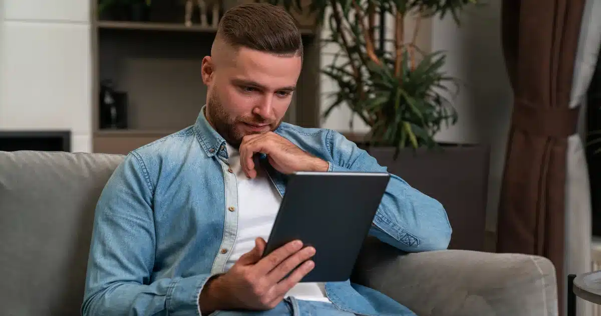A man thoughtfully reviewing a substance use self-assessment on a tablet at home A man thoughtfully reviewing a substance use self-assessment on a tablet at home