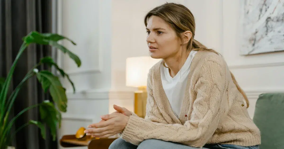 Woman sitting at home with a concerned expression, reflecting on the effects of opioid use and opioid addiction treatment in Sarasota FL Woman sitting at home with a concerned expression, reflecting on the effects of opioid use and opioid addiction treatment in Sarasota FL
